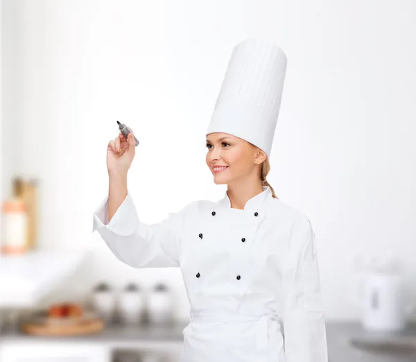 Sorrindo chef feminino escrevendo algo no ar — Fotografia de Stock