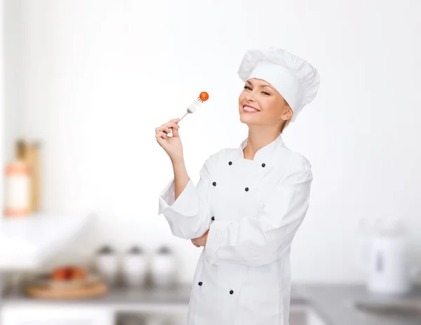 Smilende kvinnelig kokk med gaffel og tomat – stockfoto