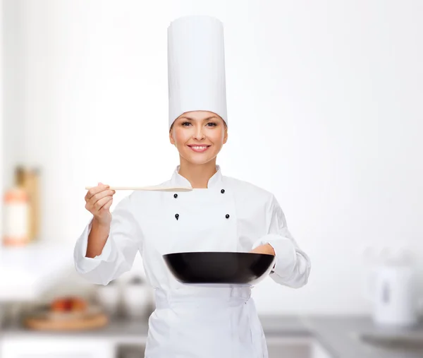 Lachende vrouwelijke chef-kok met pan- en -lepel — Stockfoto