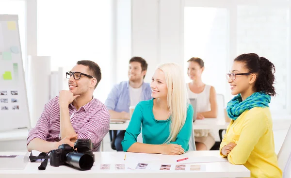 Equipo sonriente con cámara fotográfica trabajando en la oficina — Foto de Stock