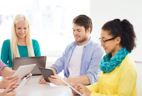 Smiling team with table pc and laptop in office — Stock Photo, Image