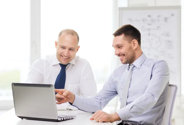 Dos hombres de negocios sonrientes con portátil en la oficina — Foto de Stock