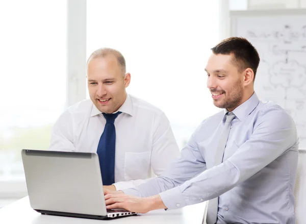 Two smiling businessmen with laptop in office — Stock Photo, Image