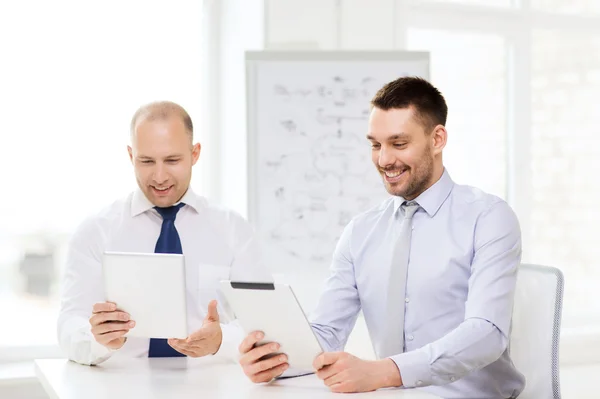 Dois empresários sorridentes com tablet pc no escritório — Fotografia de Stock