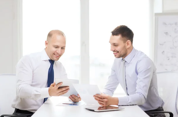 Dois empresários sorridentes com tablet pc no escritório — Fotografia de Stock