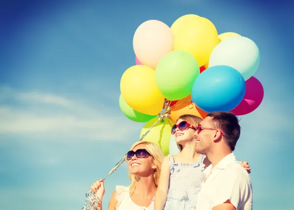 Familia feliz con globos de colores al aire libre — Foto de Stock