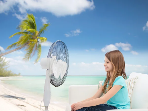 Улыбающаяся маленькая девочка с большим вентилятором дома — стоковое фото