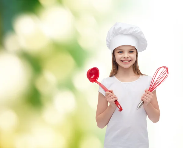 Lächelndes Mädchen mit Kochmütze mit Schöpfkelle und Schneebesen — Stockfoto