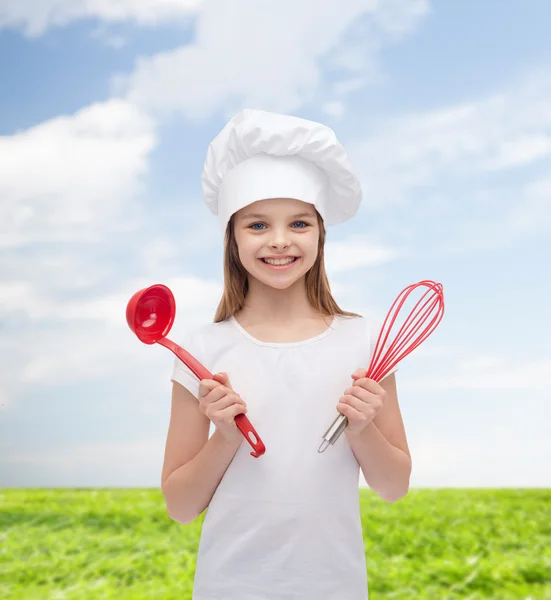 Menina sorridente em chapéu de cozinheiro com concha e batedor — Fotografia de Stock