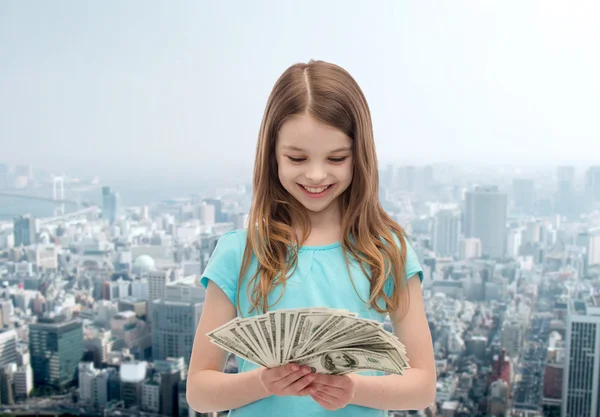 Sorrindo menina olhando para o dinheiro em dinheiro dólar — Fotografia de Stock