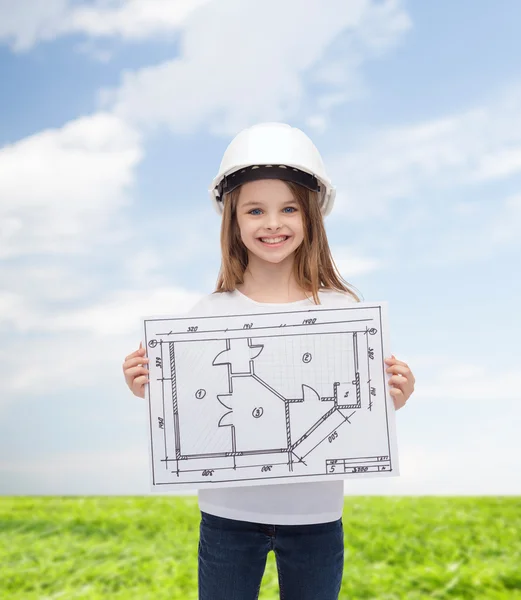 Smiling little girl in helmet showing blueprint — Stock Photo, Image