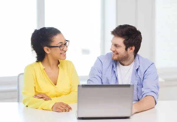 Two smiling people with laptop in office — Stock Photo, Image