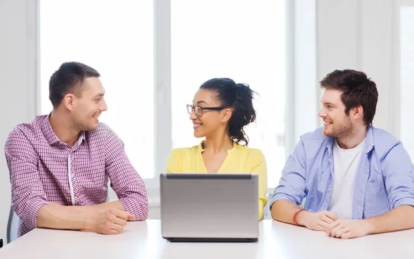 Tři usmívající se kolegové s přenosným počítačem v kanceláři — Stock fotografie