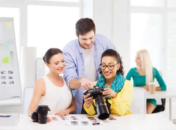 Equipo sonriente con cámara fotográfica trabajando en la oficina — Foto de Stock