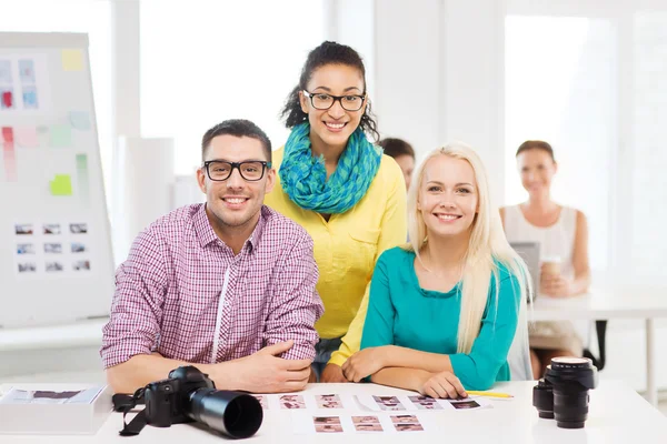 Χαμογελώντας ομάδα με τυπωμένες φωτογραφίες που εργάζονται στο γραφείο — Φωτογραφία Αρχείου