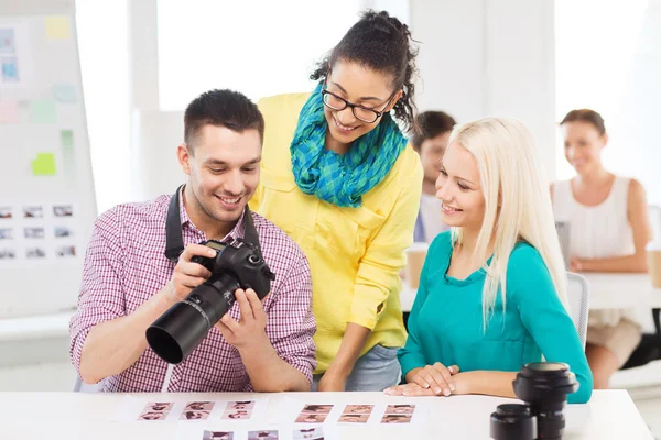 Equipo sonriente con cámara fotográfica trabajando en la oficina — Foto de Stock