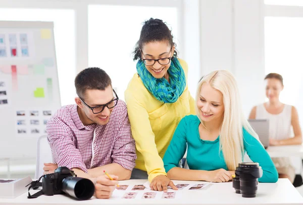 Lachende team met afgedrukte foto's werken in office — Stockfoto