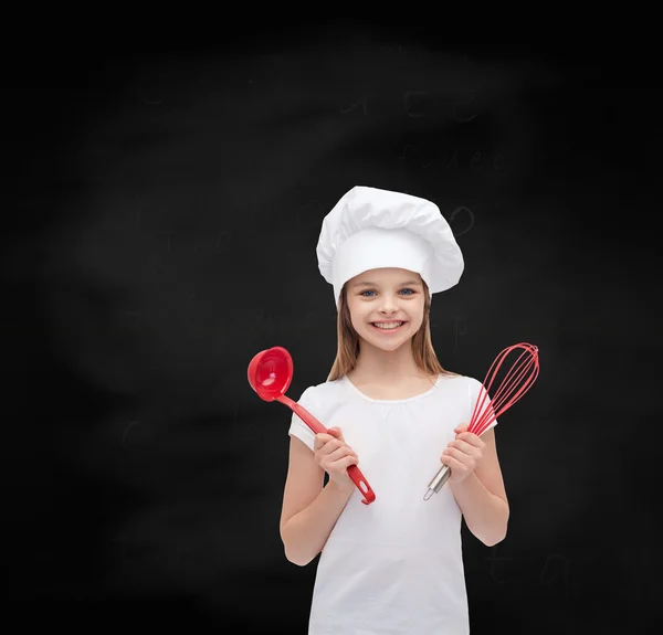 Fille souriante dans chapeau de cuisine avec louche et fouet — Photo