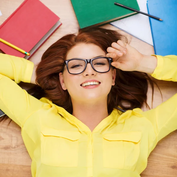 Smiling student in eyeglasses lying on floor — Stock Photo, Image