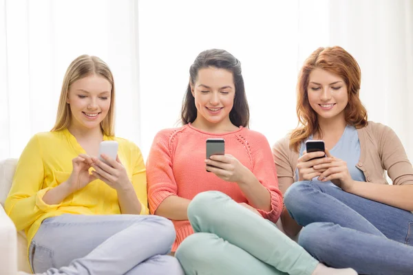 Smiling teenage girls with smartphones at home — Stock Photo, Image