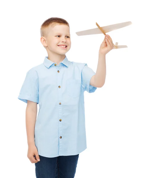 Niño sonriente sosteniendo un modelo de avión de madera — Foto de Stock