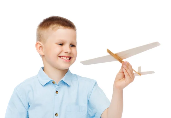 Smiling little boy holding a wooden airplane model — Stock Photo, Image