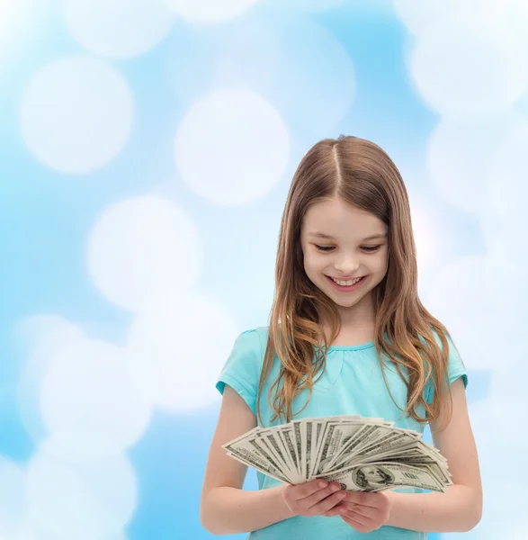 Niña sonriente mirando dinero en efectivo dólar —  Fotos de Stock