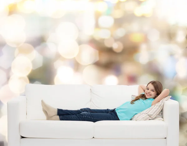 Leende liten flicka ligger på soffan — Stockfoto