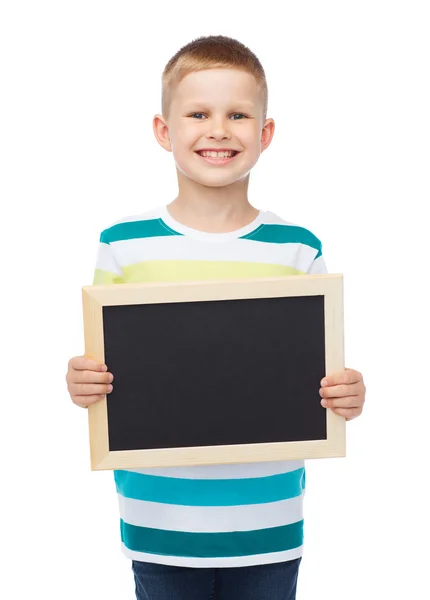 Niño sonriente sosteniendo pizarra negra en blanco — Foto de Stock