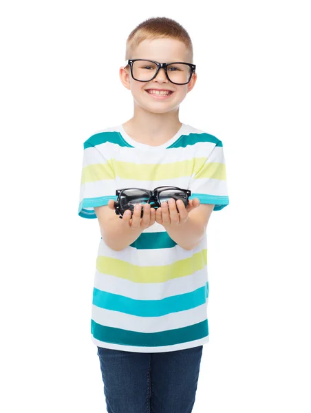 Улыбающийся мальчик в очках, держащий очки — стоковое фото
