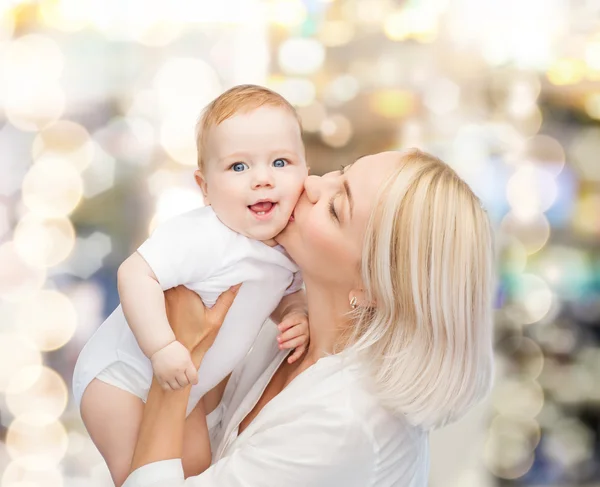 Glückliche Mutter küsst lächelndes Baby — Stockfoto