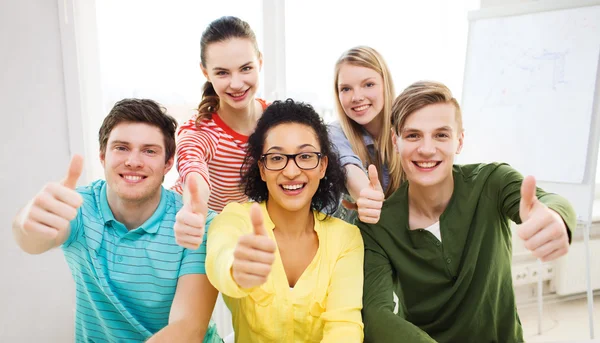 Estudiantes sonrientes en la escuela mostrando pulgares hacia arriba Imagen De Stock