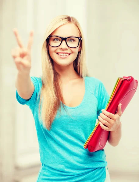 Lachende student met mappen overwinning teken weergegeven: — Stockfoto