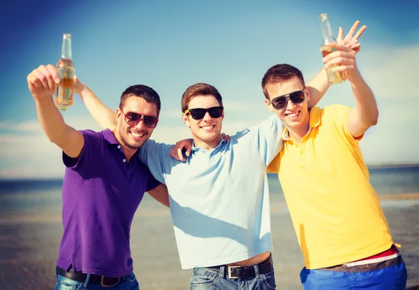 Male friends on the beach with bottles of drink — Stock Photo, Image