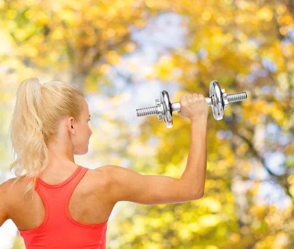 Sporty woman with heavy steel dumbbell from back — Stock Photo, Image