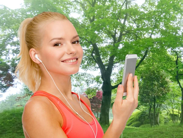 Mujer deportiva sonriente con teléfono inteligente y auriculares —  Fotos de Stock