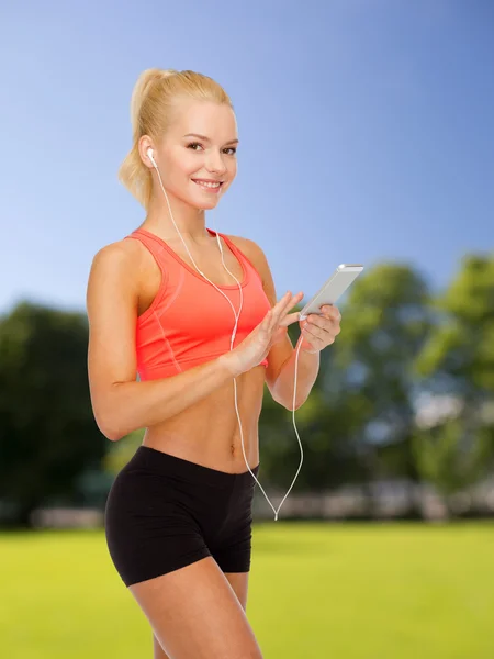 Mujer deportiva sonriente con teléfono inteligente y auriculares —  Fotos de Stock