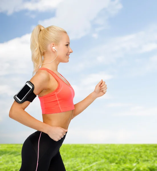 Mujer deportiva corriendo con smartphone y auriculares —  Fotos de Stock