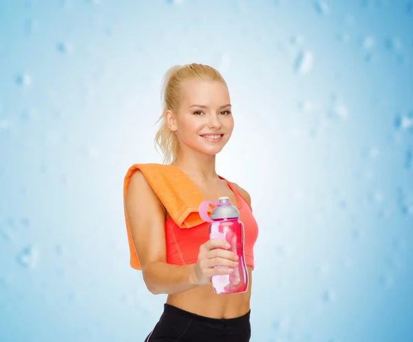 Lächelnde sportliche Frau mit Wasserflasche und Handtuch — Stockfoto