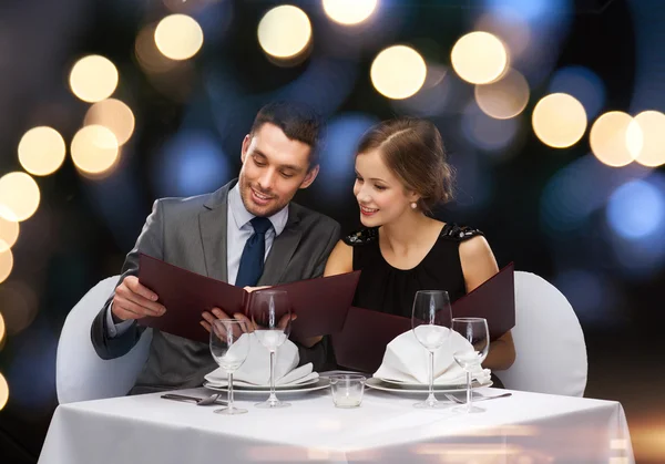 Casal sorrindo com menus no restaurante — Fotografia de Stock