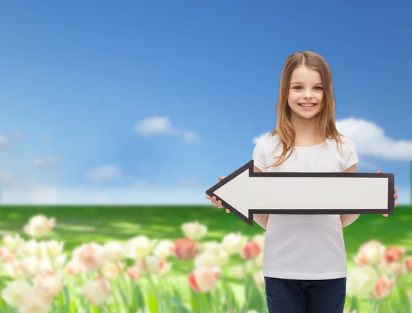 Menina sorrindo com seta em branco apontando para a esquerda — Fotografia de Stock