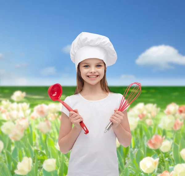 Lächelndes Mädchen mit Kochmütze mit Schöpfkelle und Schneebesen — Stockfoto