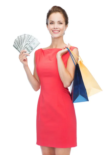 Mulher sorridente em vestido vermelho com sacos de compras — Fotografia de Stock