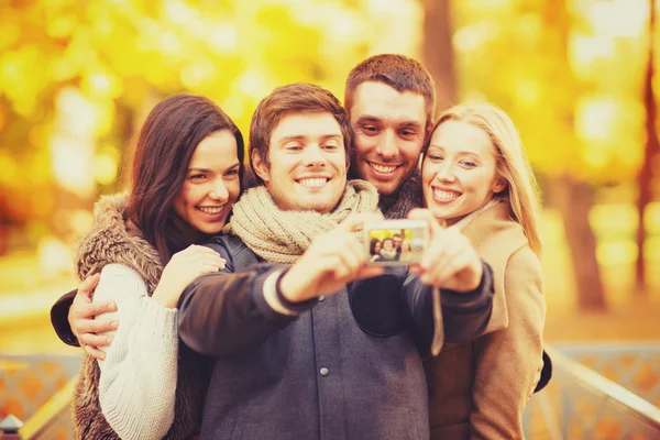 Группа друзей с фотокамерой в осеннем парке — стоковое фото