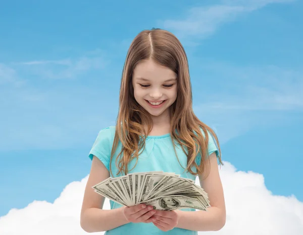 Leende liten flicka tittar på dollar i kontanter — Stockfoto