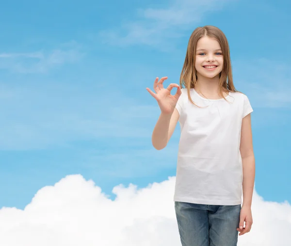 Kislány fehér pólót mutatja az ok gesztus — Stock Fotó