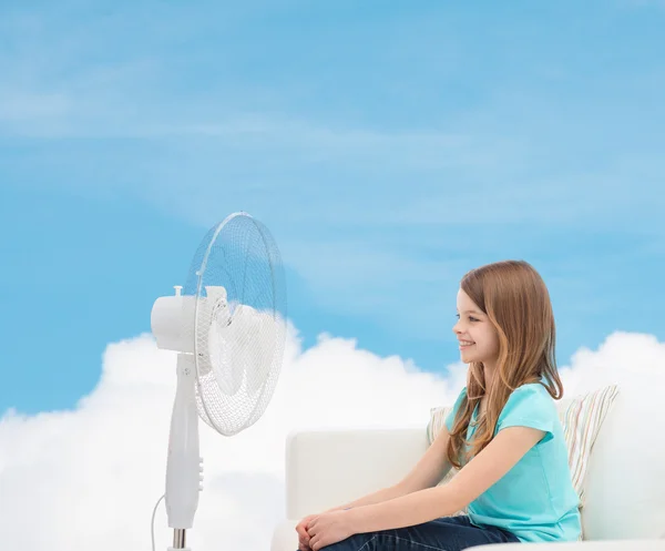 Petite fille souriante avec un grand ventilateur à la maison — Photo