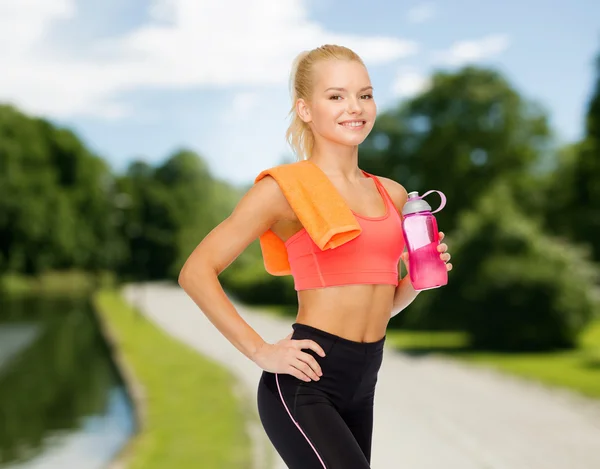Sorrindo mulher desportiva com garrafa de água e toalha — Fotografia de Stock
