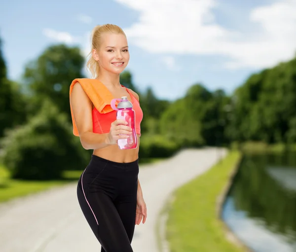 Femme sportive souriante avec bouteille d'eau et serviette — Photo