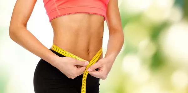 Close up of female hands measuring waist — Stock Photo, Image